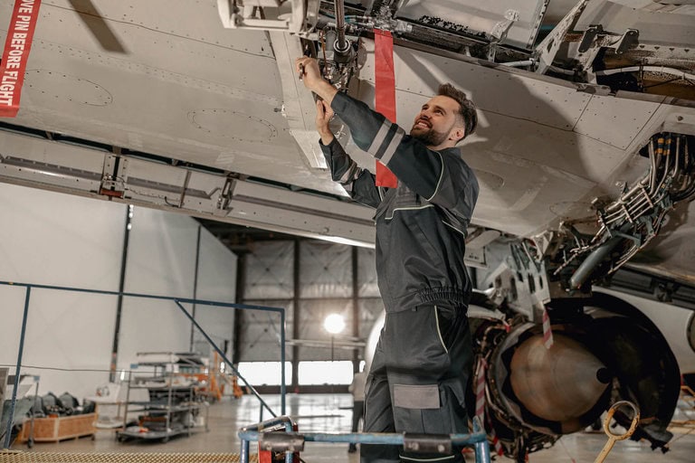 Image of an aircraft mechanic repairing an aircraft in a hangar